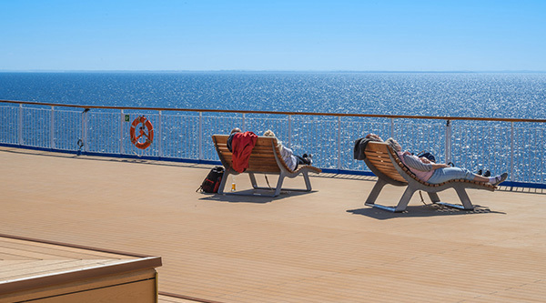 Ombord på färjan, två personer ligger i solstolar och tittar ut över havet